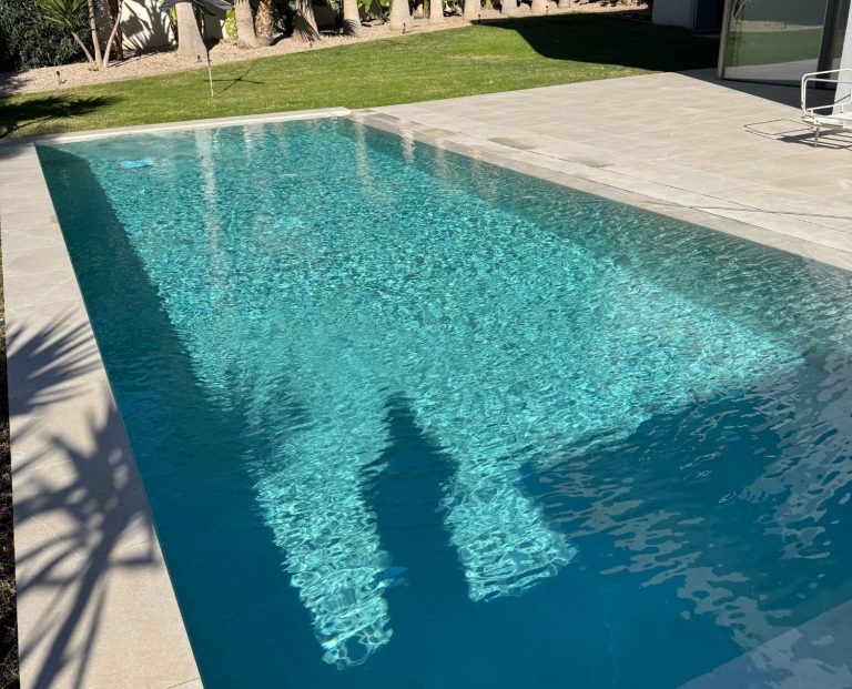 Schwimmbad Blaues Mosaikmuster im Pool, umgeben von Bäumen und modernem Mobiliar.