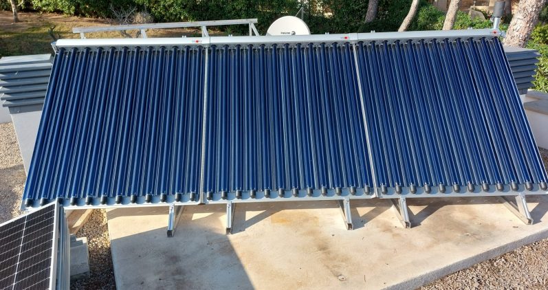Solarkollektoren auf einem Dach, blau und aus mehreren Metallröhren gefertigt.