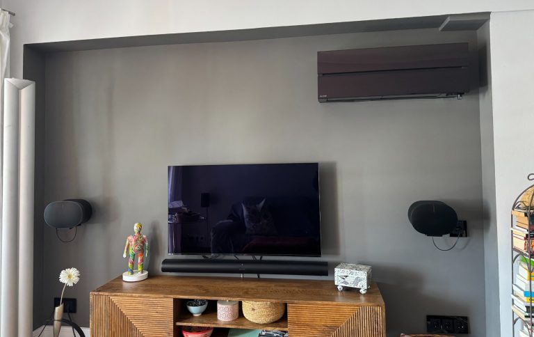 Schwarze Klimaanlage an grauer Fernsehwand mit Lautsprechern an der Wand montiert.
